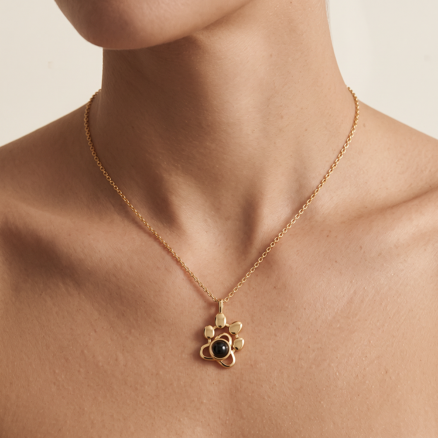 Woman wearing the LevNSoul gold-tone paw print photo projection necklace at the collarbone