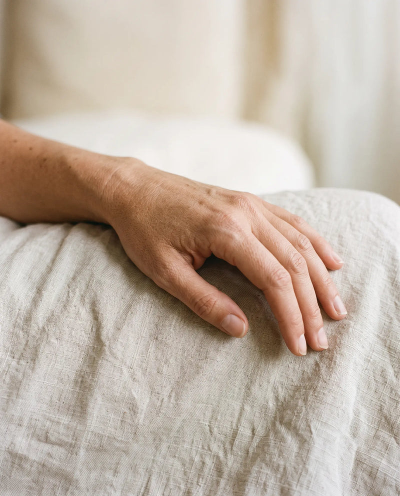 A relaxed hand and wrist resting on pale linen